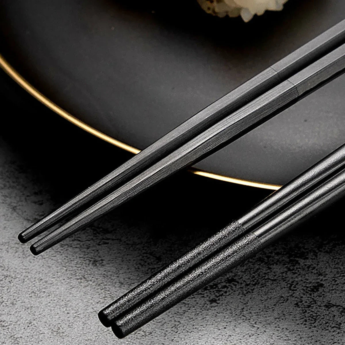 Baguettes en métal noir posées en diagonale sur fond sombre, avec effets de lumière et mise en scène artistique en arrière-plan