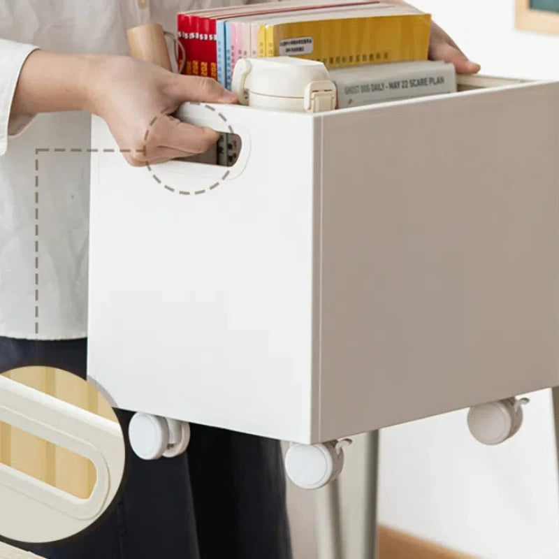 Personne transportant une boîte de rangement blanche à roulettes grâce à sa poignée intégrée – remplie de livres et accessoires, idéale pour bureau mobile.