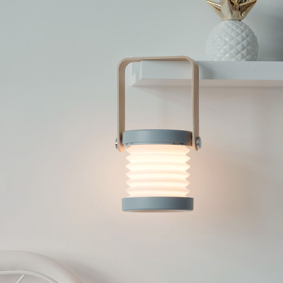 Lampe LED pliable allumée suspendue sous une étagère – lumière chaude et douce pour créer une ambiance cosy dans un intérieur moderne.