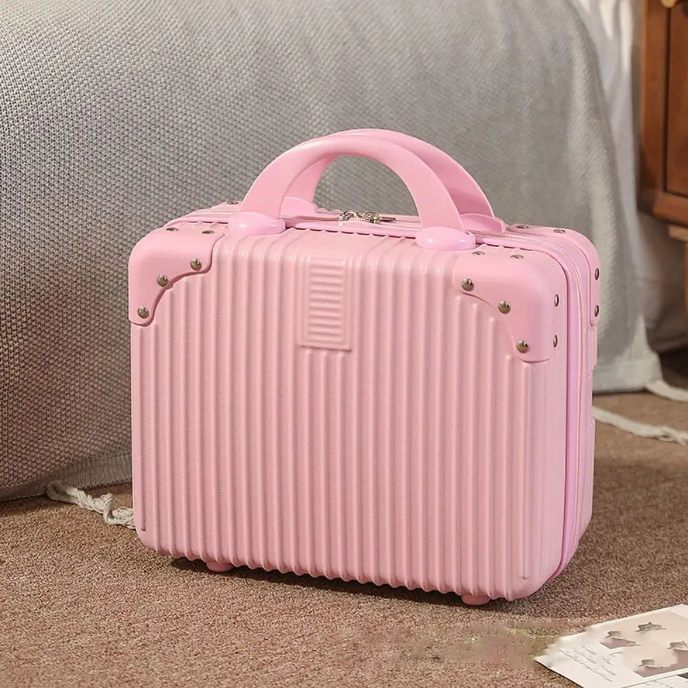 Mini valise rigide rose poudré avec poignée, posée sur un tapis, idéale pour le maquillage, les accessoires ou les voyages